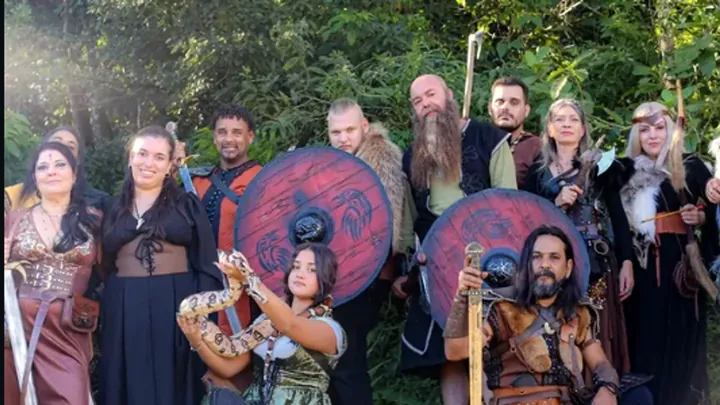 Grupo em trajes medievais e nórdicos com escudos, em um encontro ao ar livre