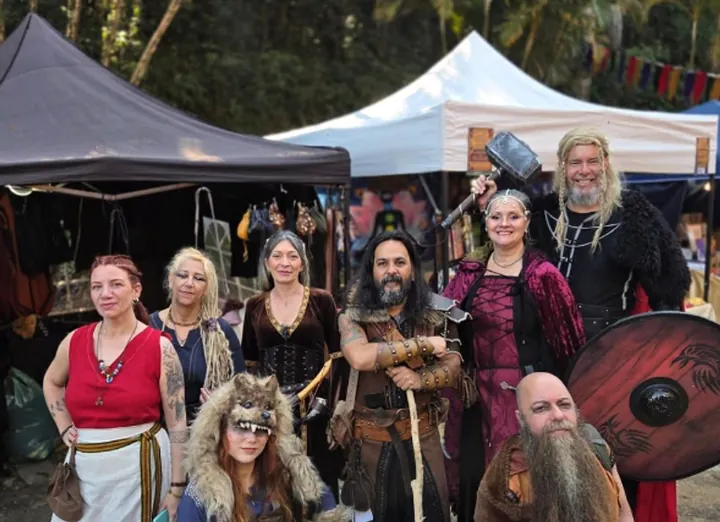 Grupo em trajes medievais e nórdicos entre tendas de uma feira